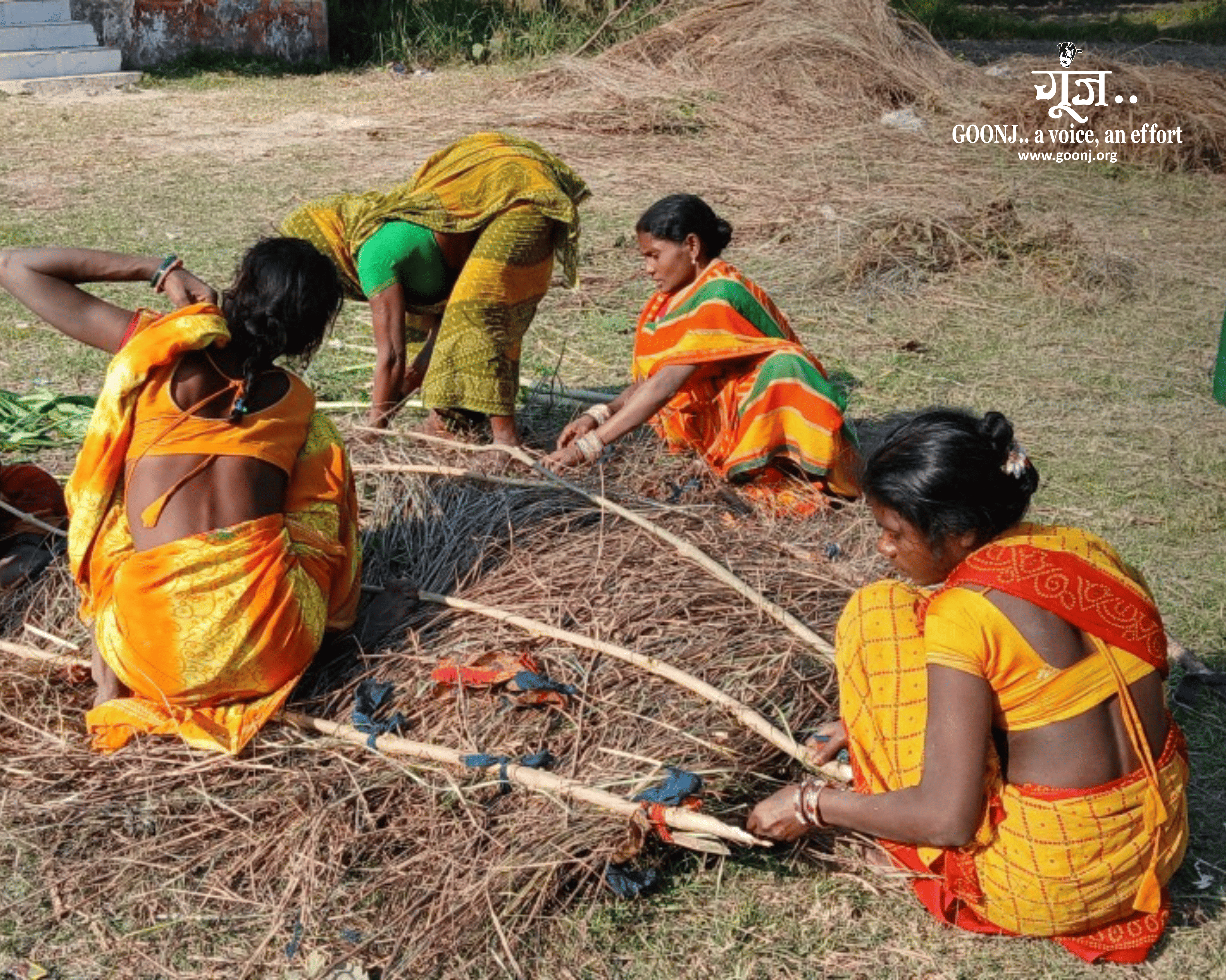 Women use local bamboo and dry grass to build a screen around the village handpump.